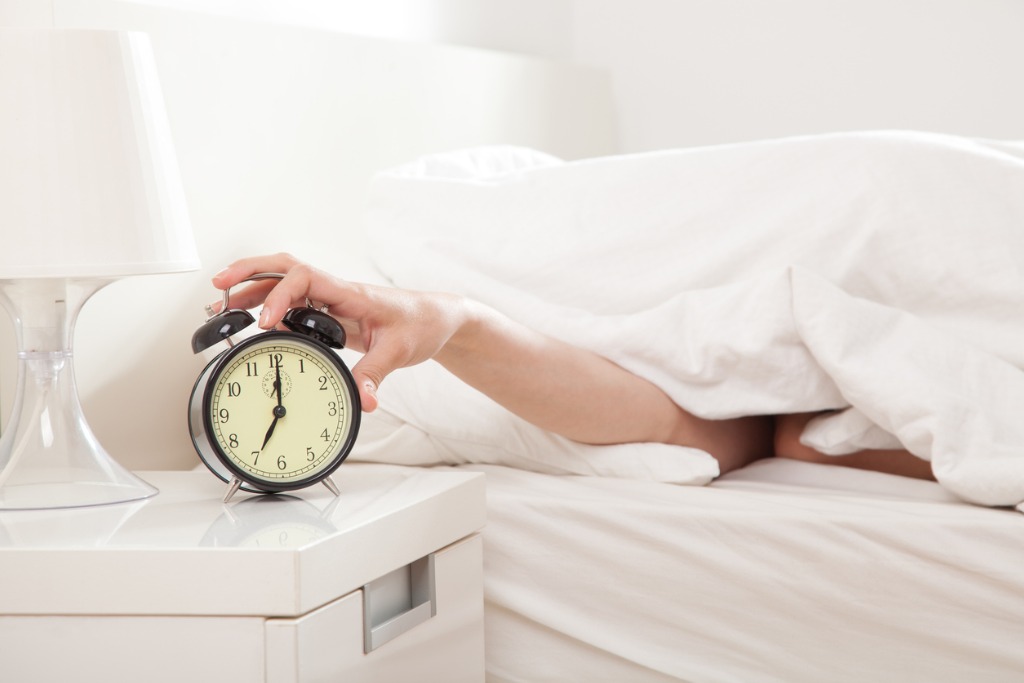 person using alarm clock in the morning as they suffer from jet lag